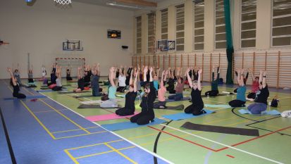 Kilkadziesiąt osób ćwiczy jogę w sali gimnastycznej
