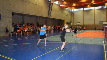 Grupa osób gra w badmintona na sali gimnastycznej