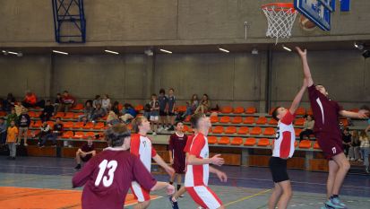 Grupa chłopców grających w koszykówkę w hali sportowej