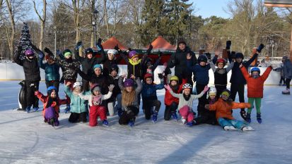 Grupa dzieci na lodowisku miejskim w parku.