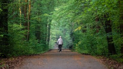 Starszy mężczyzna idzie przez las 